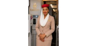 Emirates cabin crew member in uniform standing inside an aircraft cabin